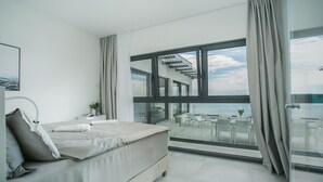 Een moderne slaapkamer met een groot bed, een nachtkastje, en uitzicht op een balkon met tuinmeubilair.