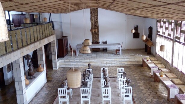 A spacious room with a high ceiling, a central seating area, and a balcony with a railing.