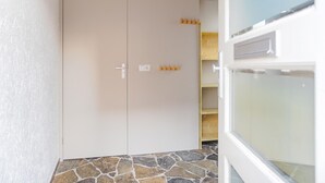A room with a stone floor, a white door, and a wooden ceiling. - Vacation Home 450 m From the Beach (Katwijk Aan Zee)