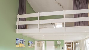 A room with a bunk bed, green walls, a clock, and a door leading to another room. - Vacation Home 450 m From the Beach (Katwijk Aan Zee)