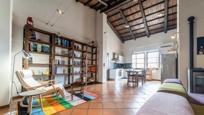 A spacious living area with a high ceiling, a wooden bookshelf, a dining table with chairs, a sofa, and a kitchen in the background. - Welcomely- In Barberia Milis (Milis)