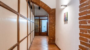 A hallway with a tiled floor, a wooden door, and a brick wall. - Welcomely- In Barberia Milis (Milis)