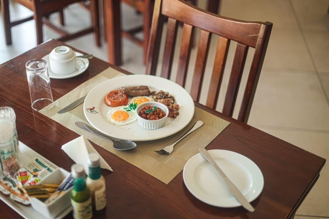 A dining table with a plate of food, a cup, and condiments.