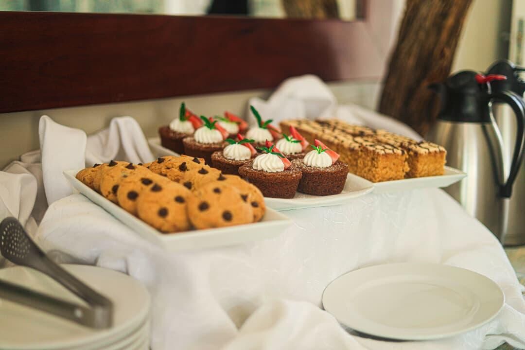 A table with various baked goods, including cookies and muffins, arranged on a white cloth.