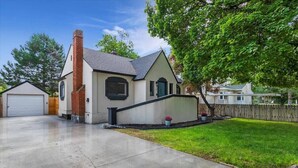 A single-story house with a garage, a brick chimney, and a well-maintained lawn. - #StayinMyDistrict TwinFalls Tudor (Twin Falls)