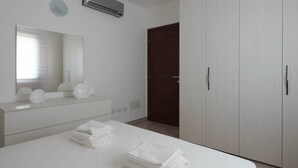 A bedroom with a bed, a dresser, a mirror, and a wardrobe.