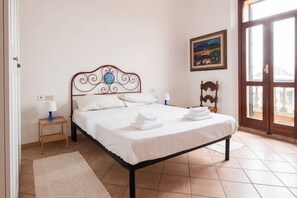 A neatly made bed with white linens, a wooden headboard, and a small bedside table with a lamp.