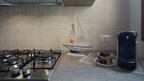 A kitchen with a gas stove, a hanging kitchen towel, and a coffee maker.