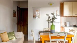 Un salon confortable avec un canapé, une table à manger et des chaises, ainsi qu’un coin cuisine équipé de placards et d’un évier.