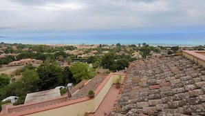 A coastal town with terracotta-roofed buildings, a view of the sea, and a cloudy sky. - Welcomely - Villa Paola B (Muravera)