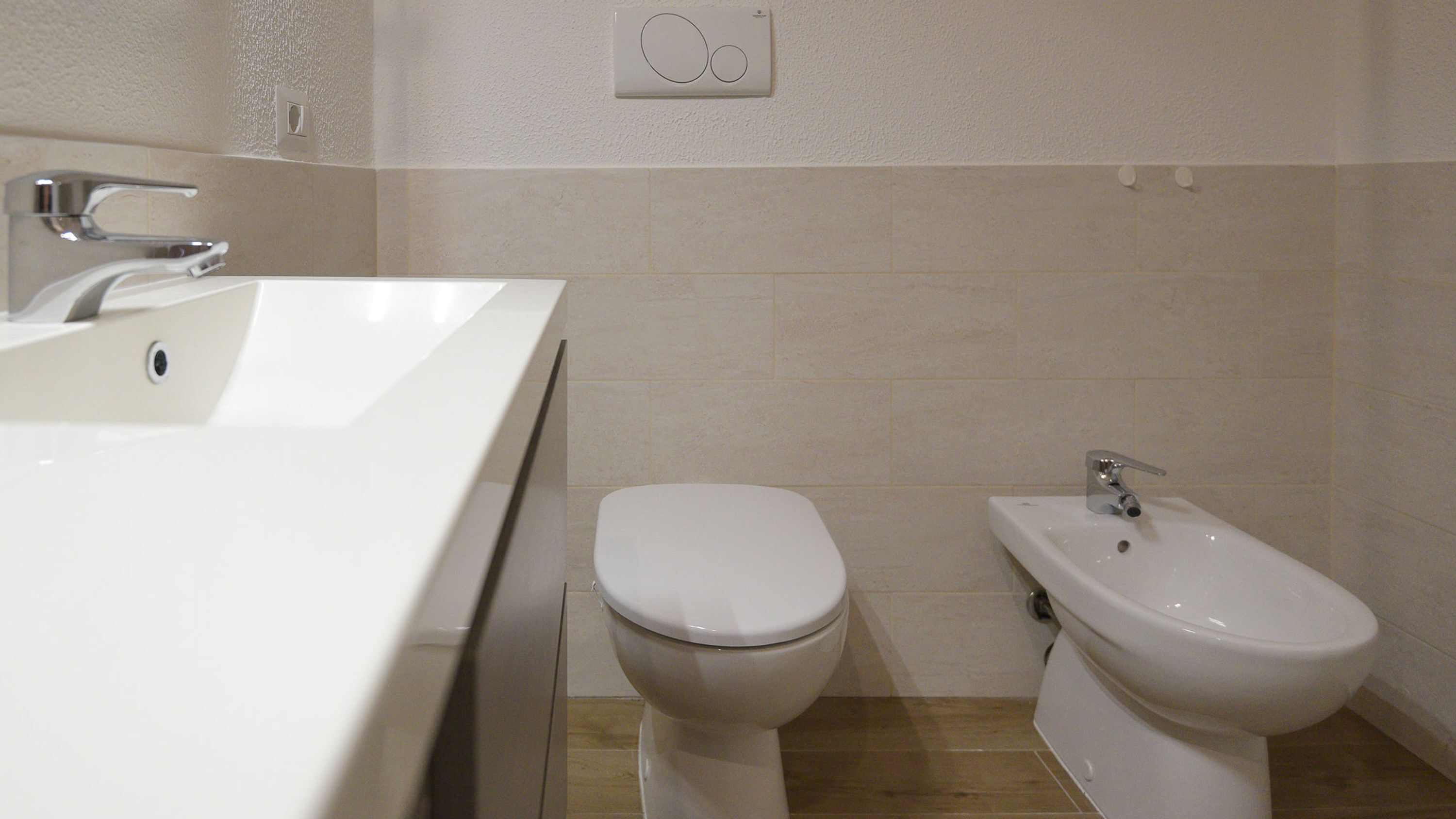 A bathroom with a white sink, toilet, and bidet.