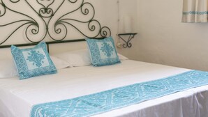 A bed with white bedding and two decorative pillows with blue patterns. - Casa Oliveto 1 in Galtell (Galtelli)