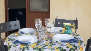 A round table set for four with clear glassware, a pitcher, and a floral tablecloth. - Casa Oliveto 1 in Galtell (Galtelli)