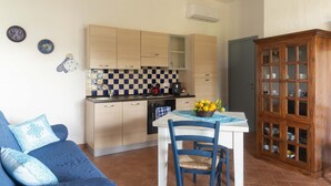 A compact kitchen with a checkered backsplash, a dining table with chairs, and a cabinet with glass doors. - Casa Oliveto 1 in Galtell (Galtelli)