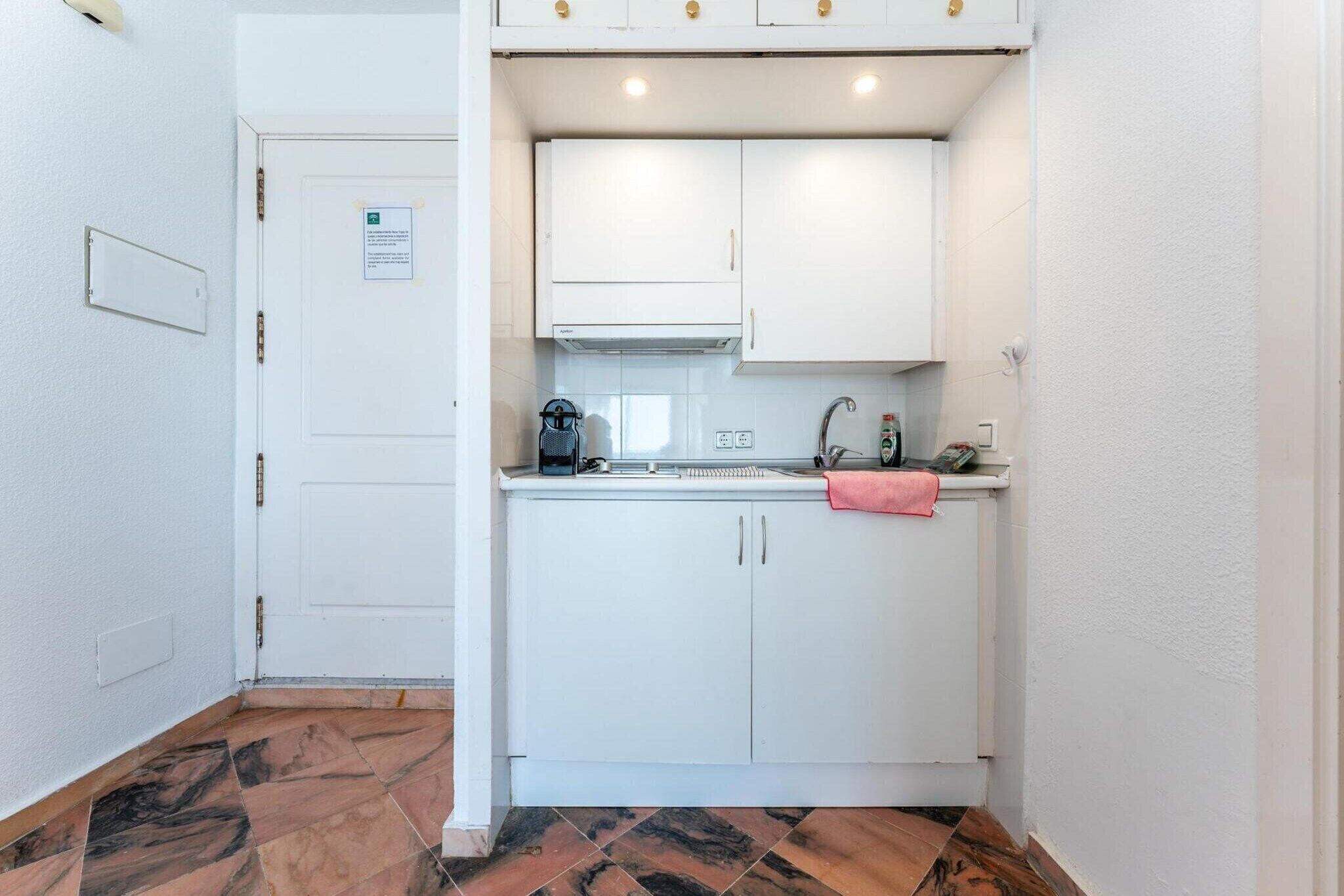 Una cucina compatta con mobili bianchi, un piano di lavoro e un piccolo lavello.