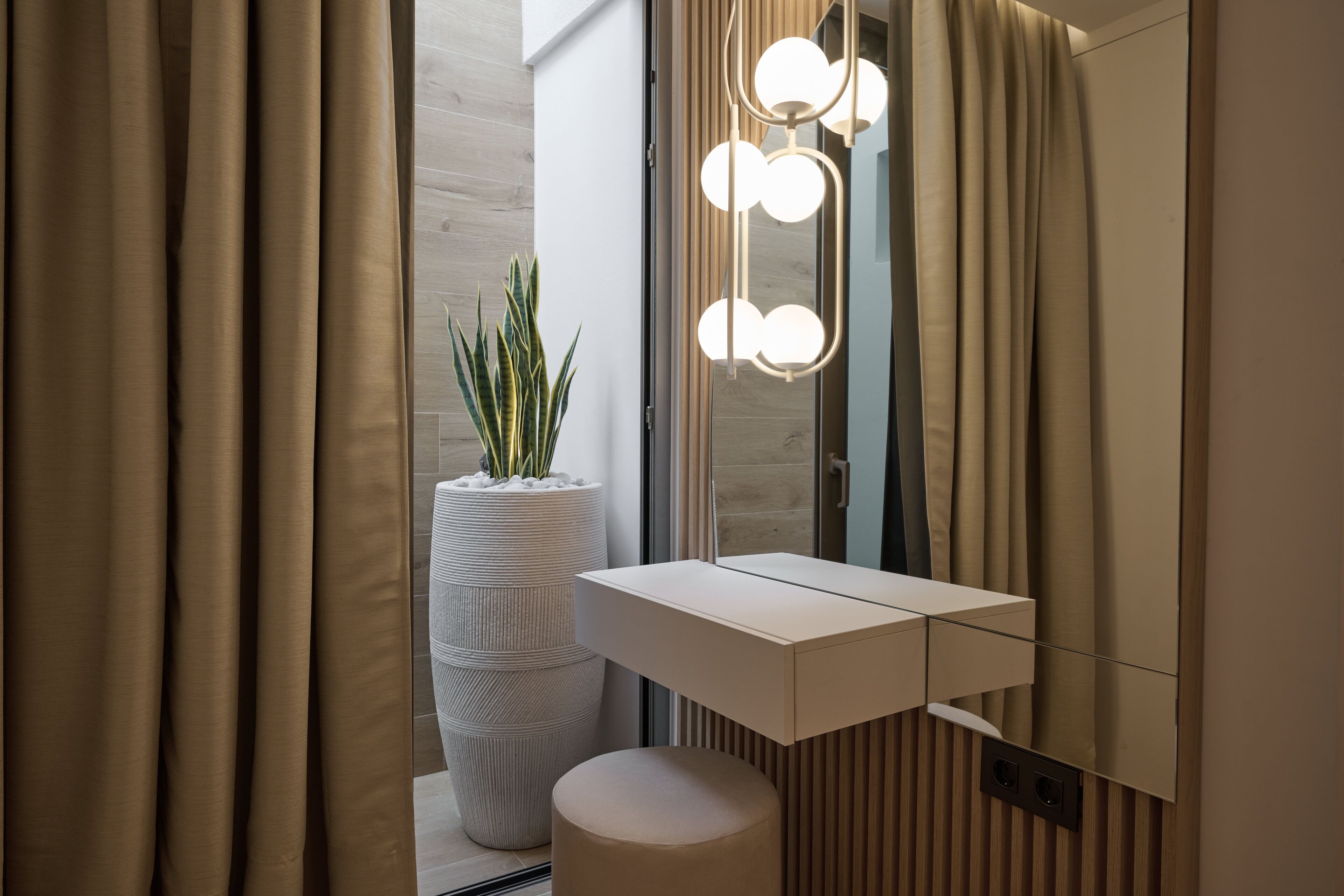 A modern bathroom with a white vanity, a large mirror, and a potted plant.
