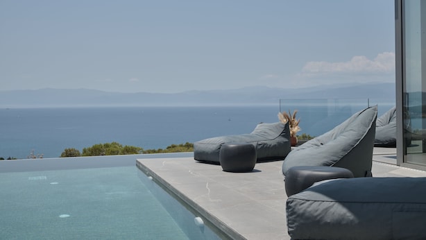 A modern outdoor seating area with a pool, overlooking a scenic ocean view. - Porphyra Collection Villas Porto Heli  (Ermionida)