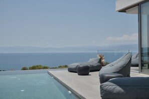 Un espacio moderno de estar al aire libre con piscina, con vistas a un paisaje marino.