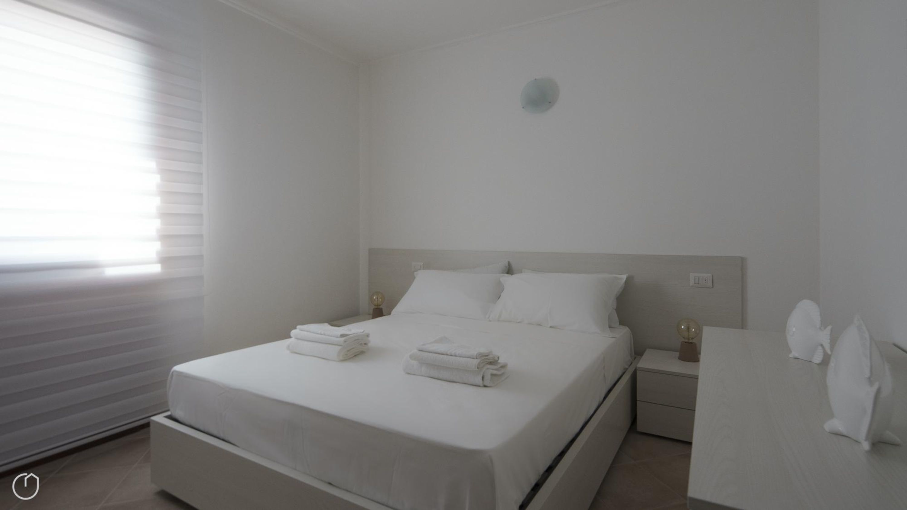 A minimalist bedroom with a bed, bedside tables, and a nightstand.
