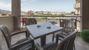 A balcony with a table and chairs, overlooking a road and buildings. - Welcomely- Xenia Boutique House - Apt 12 (Olbia)