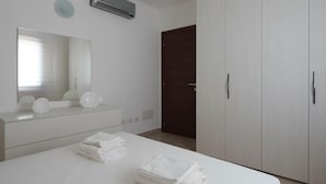 A bedroom with a bed, a dresser, a mirror, and a wardrobe. - Welcomely- Xenia Boutique House - Apt 11 (Olbia)