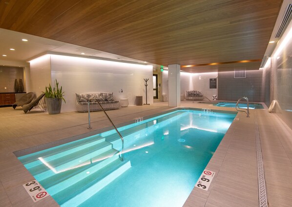 Une piscine intérieure à l’eau claire, dotée d’indications claires de profondeur et d’un plafond en bois.
