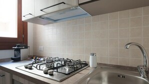 A modern kitchen with a gas stove, stainless steel sink, and a window providing natural light. - Welcomley - Xenia Boutique House - Apt 5 (Olbia)