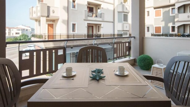 A balcony with a table set for two, chairs, and a small potted plant. - Welcomley - Xenia Boutique House - Apt 5 (Olbia)