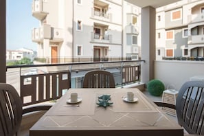 A balcony with a table set for two, chairs, and a small potted plant. - Welcomley - Xenia Boutique House - Apt 5 (Olbia)