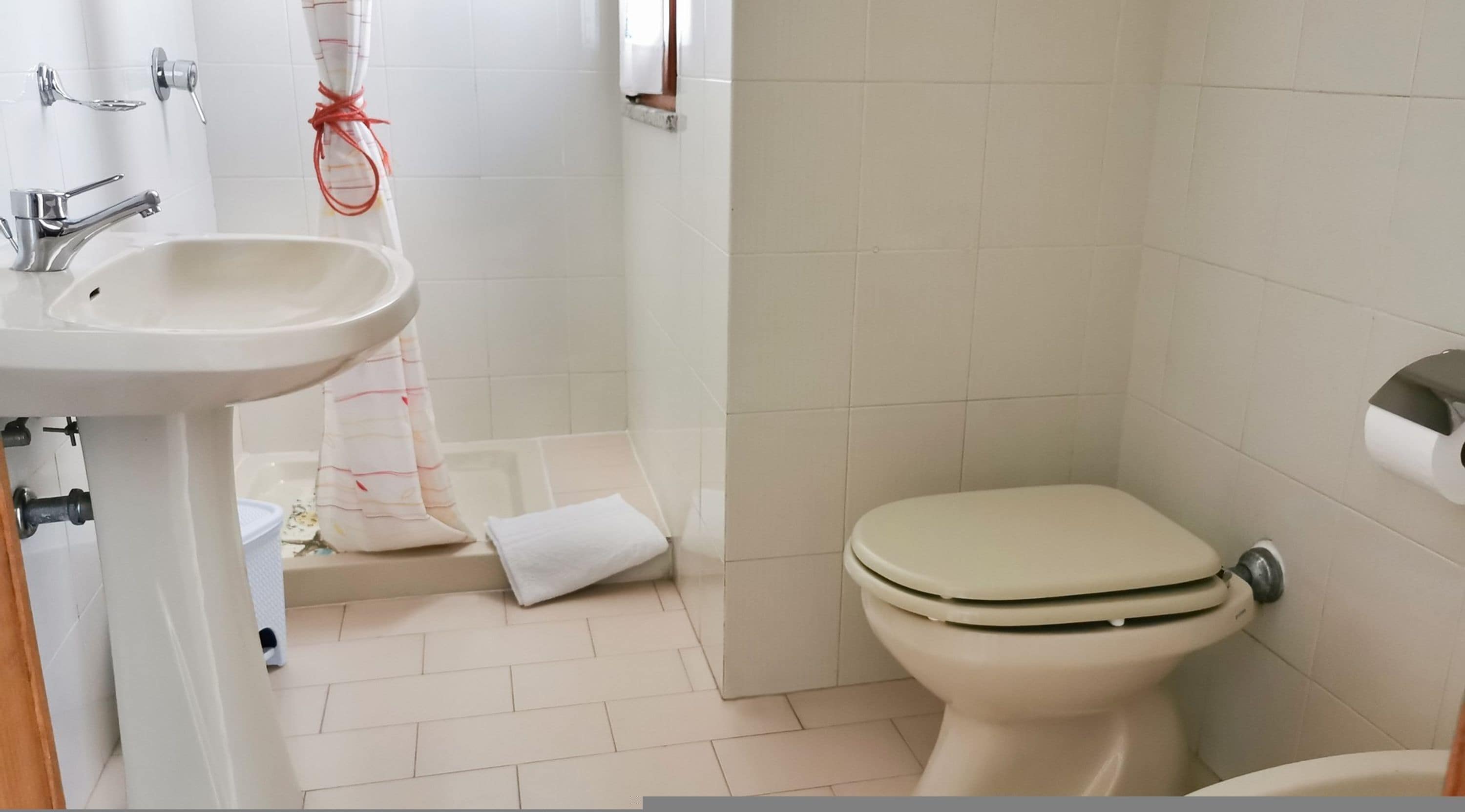 Un bagno con lavandino, WC e tenda per la doccia.
