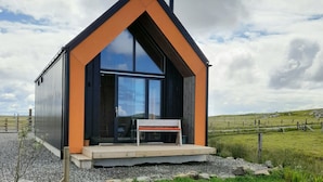 A modern, single-story house with a prominent black roof and orange walls. - North Light Studio (Isle of North Uist)