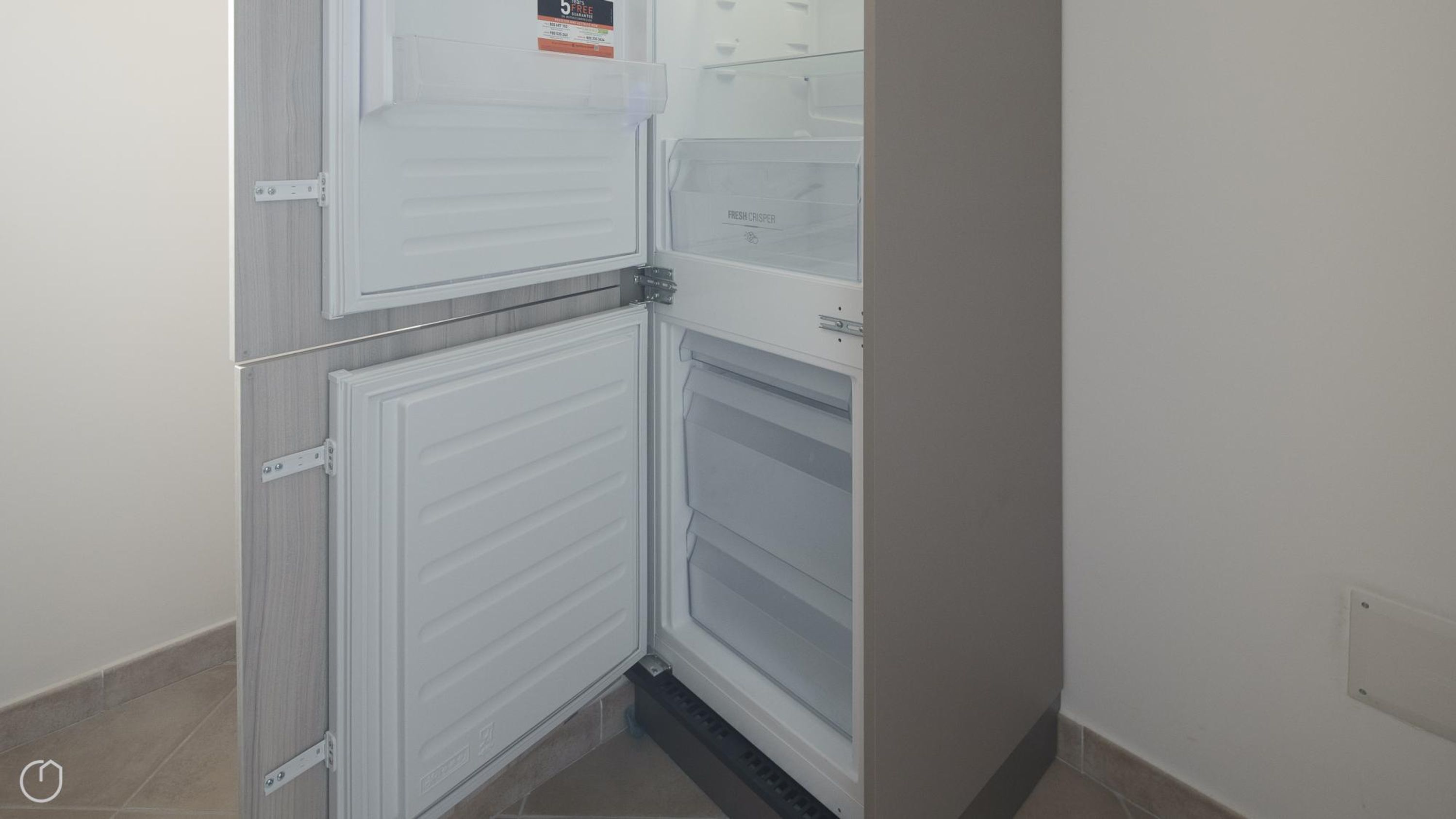 A compact kitchen with a built-in refrigerator and a microwave.