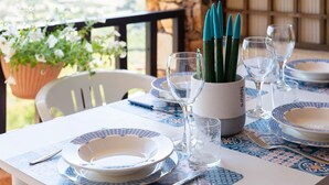 A table set with blue and white patterned tableware, clear glassware, and a green plant in a white pot. - Welcomely - Casa Della Luna (Budoni)