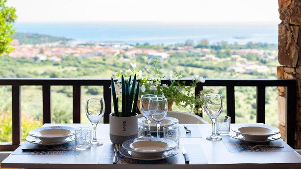 A table set for dining with a view of a coastal landscape. - Welcomely - Casa Della Luna (Budoni)
