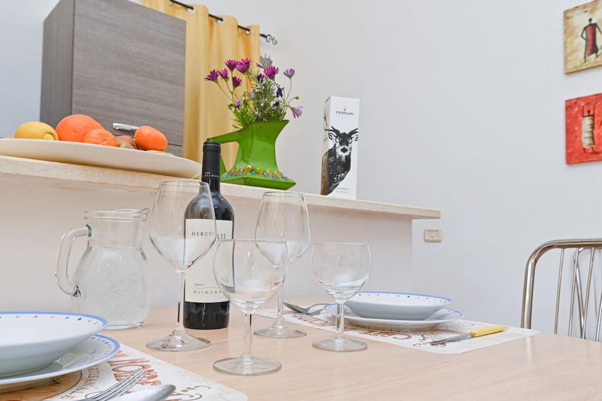 A dining table with wine glasses, a bottle of wine, and a vase with flowers.