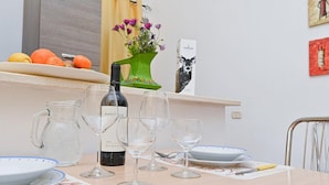 A dining table with wine glasses, a bottle of wine, and a vase with flowers. - Welcomely - Villa Alba (Muravera)