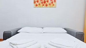 A neatly made bed with white linens and pillows, a gray headboard, and a wall art piece above. - Welcomely - Villa Alba (Muravera)