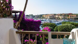 A balcony with a view of a marina and buildings in the background. - Welcomely - Porto Cervo sul Mare (Arzachena)
