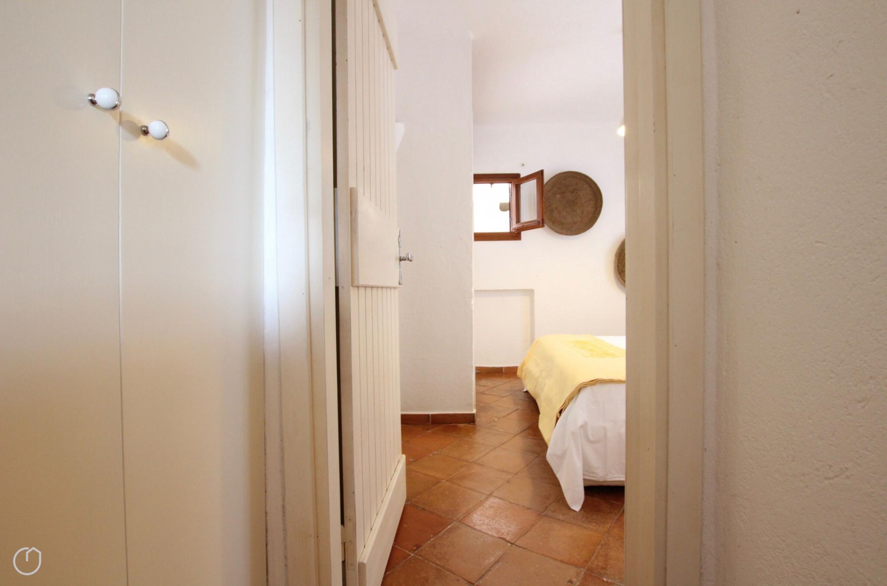 Un pasillo estrecho que conduce a un dormitorio con una cama cubierta con una manta amarilla.