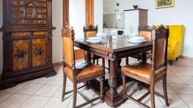 Un comedor con una mesa y sillas de madera, un mueble grande de madera y una silla amarilla.