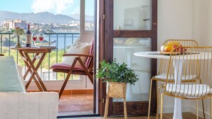 Ein Balkon mit Tisch und Stühlen, einer Topfpflanze und Blick auf eine Stadtansicht.