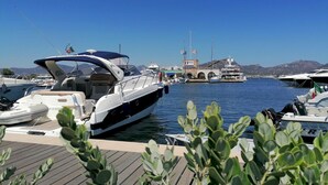 Ein Yachthafen mit mehreren dort angestuften Booten, einer Holzterrasse und blauem Himmel.