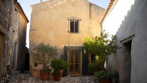 A narrow alleyway with a building featuring a small window and a door. There are potted plants and a stone-paved ground. - Welcomely - Casa Tipica Vista Mozzafiato (Posada)