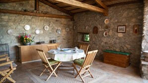 A rustic stone-walled dining area with a round table set for two, wooden chairs, and a wooden bench. - Welcomely - Casa Tipica Vista Mozzafiato (Posada)