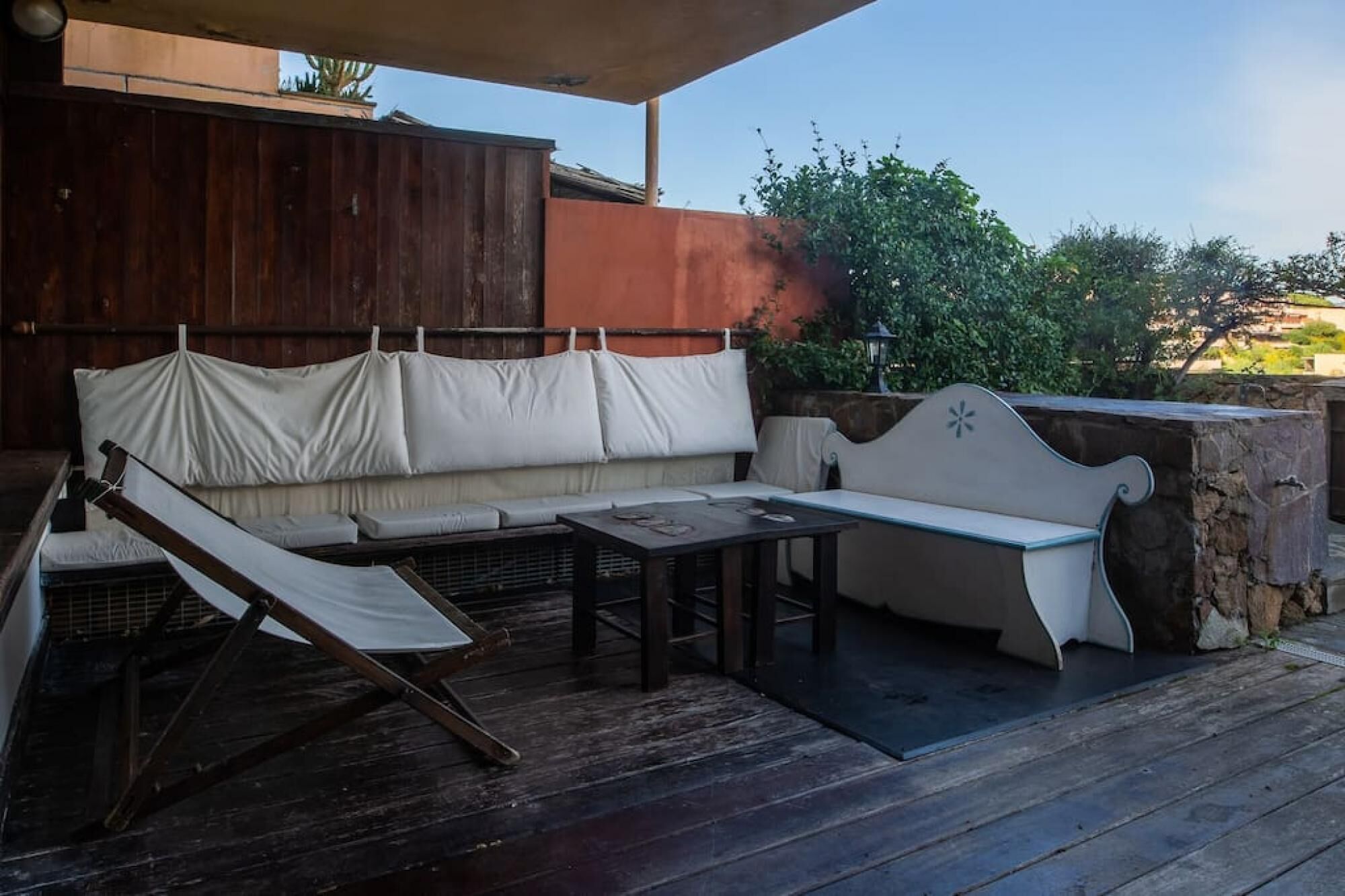 Un espace extérieur aménagé avec une terrasse en bois, un banc rembourré et une table.