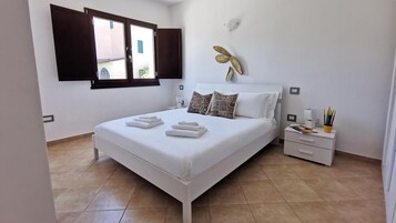 Un dormitorio ordenado con cama, almohadas, una mesita de noche y un adorno en la pared.