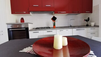 Una cocina moderna con armarios rojos, una estufa a gas y una mesa de comedor con un tazón rojo y velas.