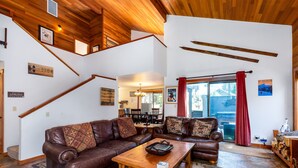 Ein geräumiges Wohnzimmer mit einem braunen Ledersofa, einem Holztisch und einer Treppe mit hölzernen Geländern.