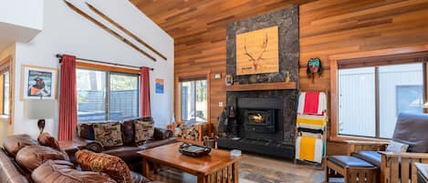 Un salón amplio con chimenea, sofás de cuero y una pared de acento de piedra.