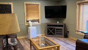 A living room with a wooden coffee table, leather sofa, and a flat-screen TV mounted on the wall.